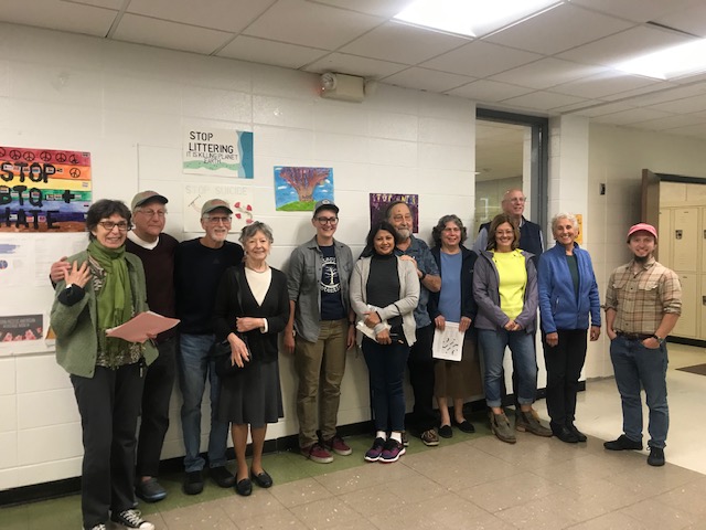 Twelve adults posing in a school hallway 