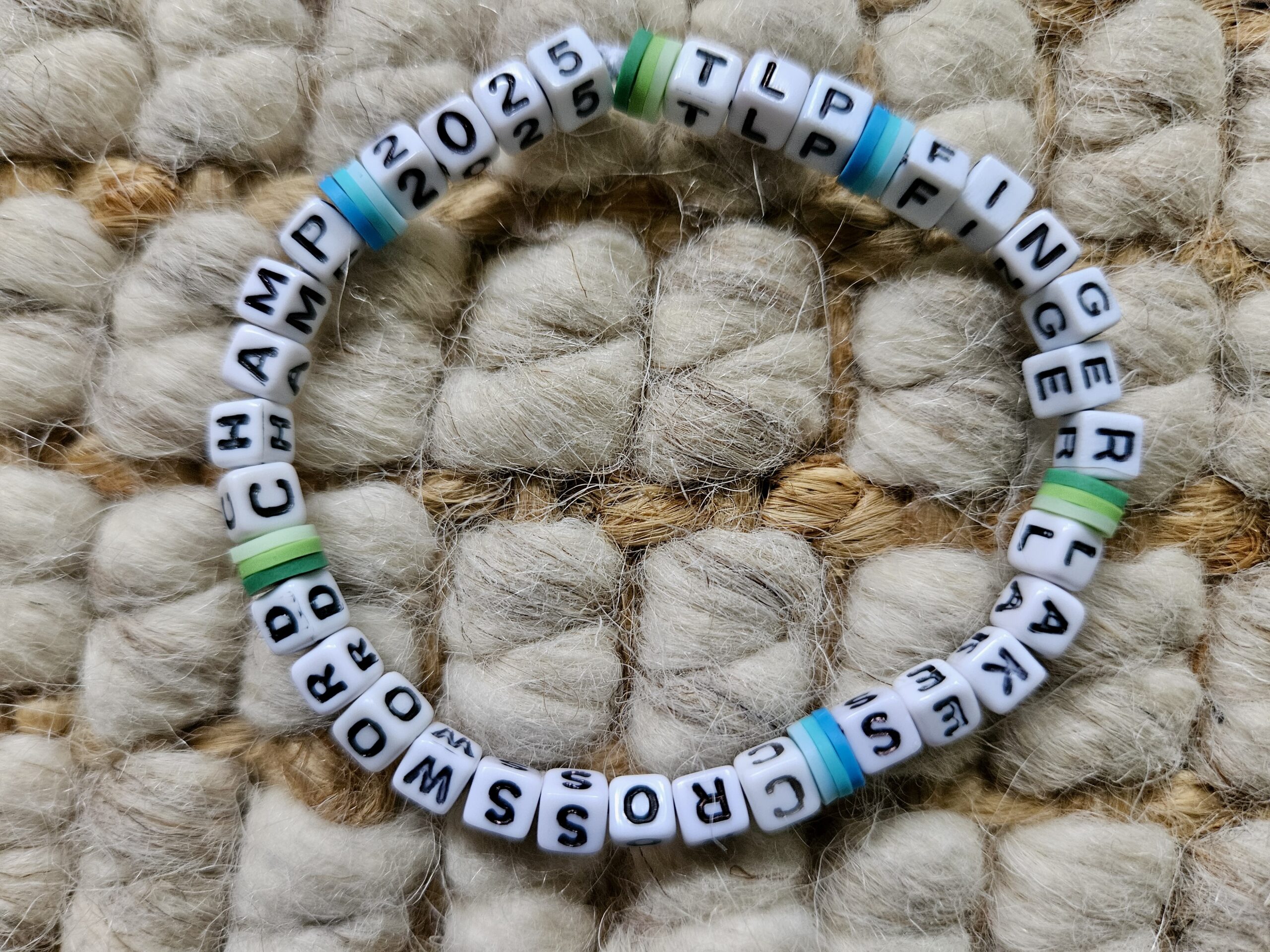 Handmade bracelet with beads spelling out "2025 TLP FINGER LAKES CROSSWORD CHAMP"