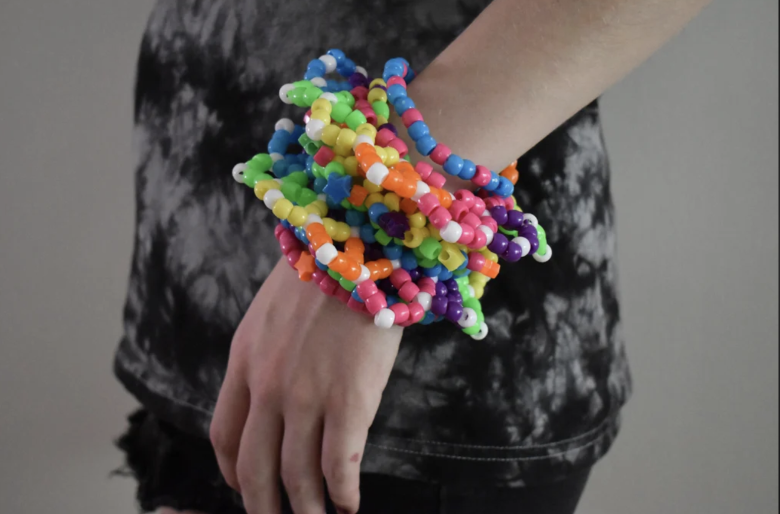 Person in a black shirt wearing a large complicated bead bracelet on their wrist